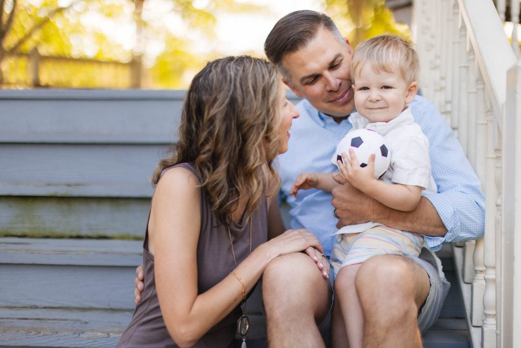 A family sits on the steps at Quiet Waters Park, holding a soccer ball.