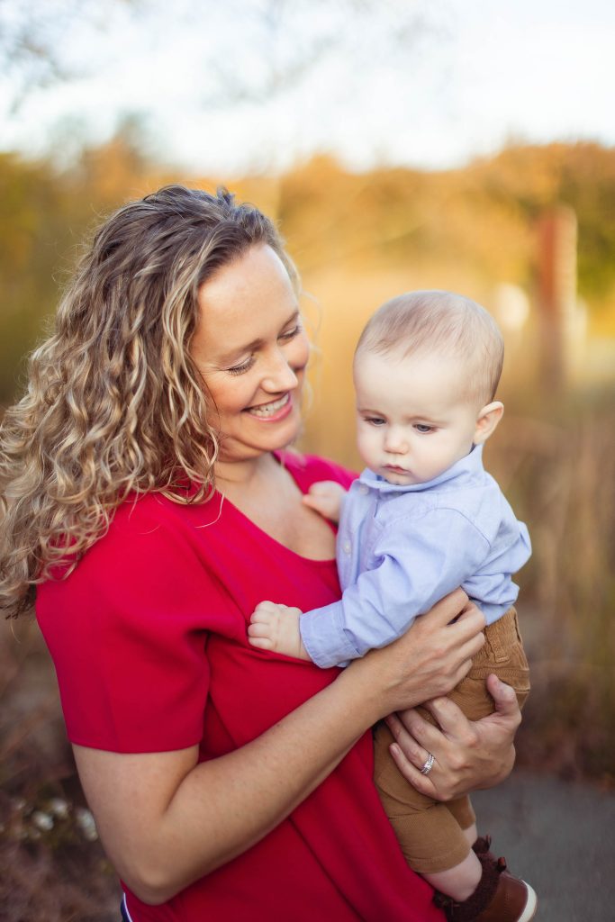A woman holding a baby in a red shirt for a family portrait in Annapolis, Maryland.