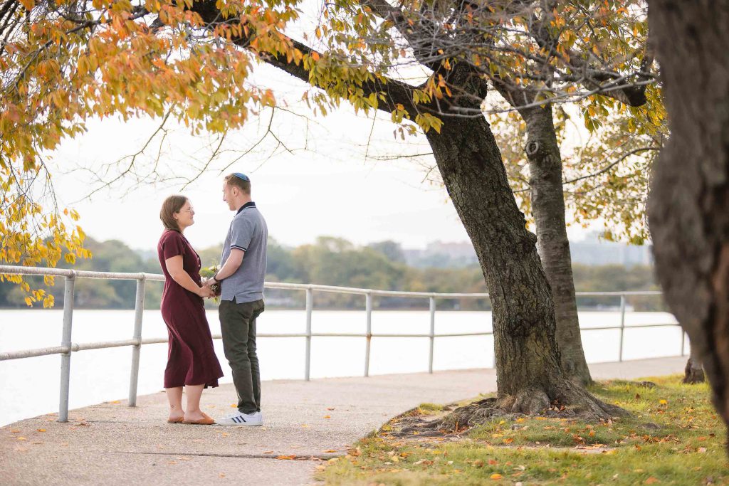 A couple standing next to each other on a walkway near the water in Washington DC.