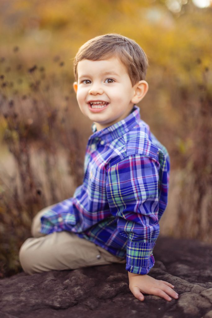 A young boy sitting in Quiet Waters Park in Annapolis, Maryland during the fall.