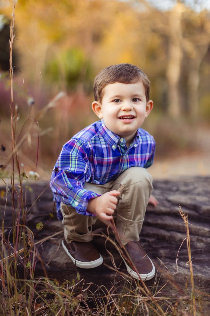 A young boy crouching on a log in Quiet Waters Park in Annapolis Maryland.