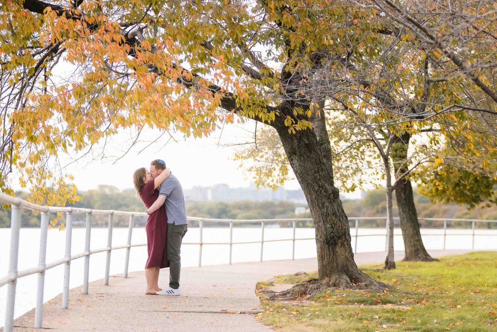 A couple sharing a surprise kiss near the Tidal Basin.