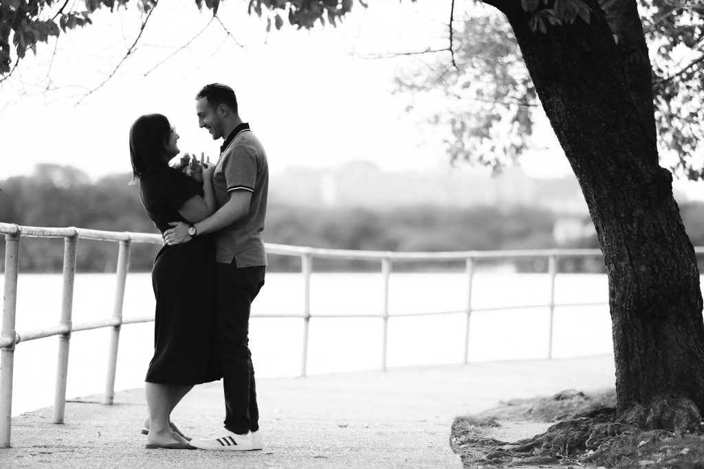 A black and white photo of a couple embracing near the Tidal Basin in Washington DC.