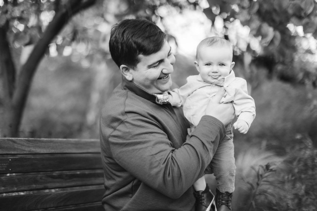 A black and white photo of a family in Annapolis, Maryland, showing a man holding a baby on a bench.