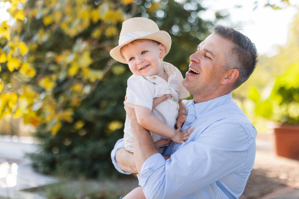 A man holding a baby in his arms in a park for a family portrait.
