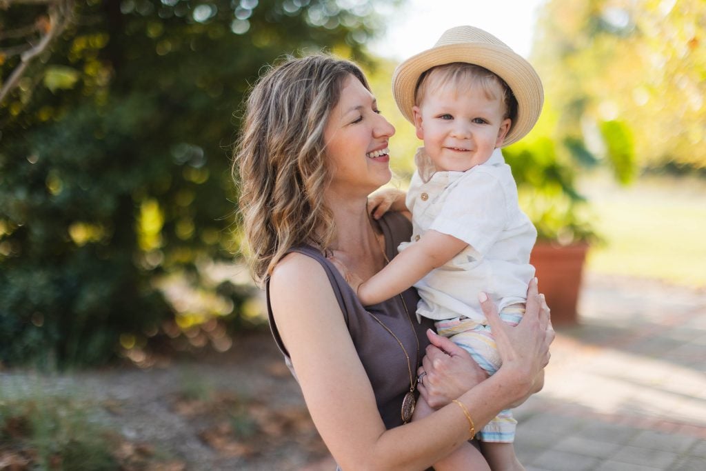 A woman holding her son in a hat, capturing a heartwarming family moment in a park.