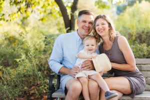 A family from Annapolis sits on a bench with a baby on their lap, capturing beautiful family portraits.