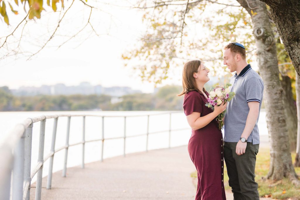 An engaged couple standing next to a tree near the Surprise Proposal spot at Tidal Basin.