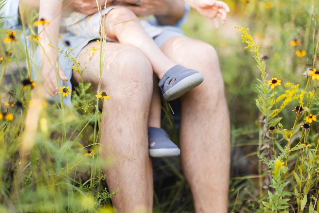 A man holding a child among a field of wildflowers in Annapolis, capturing beautiful family portraits.