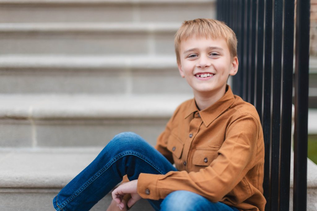 A young boy sitting on the steps of a staircase at Belair Mansion, perfect for family portraits.