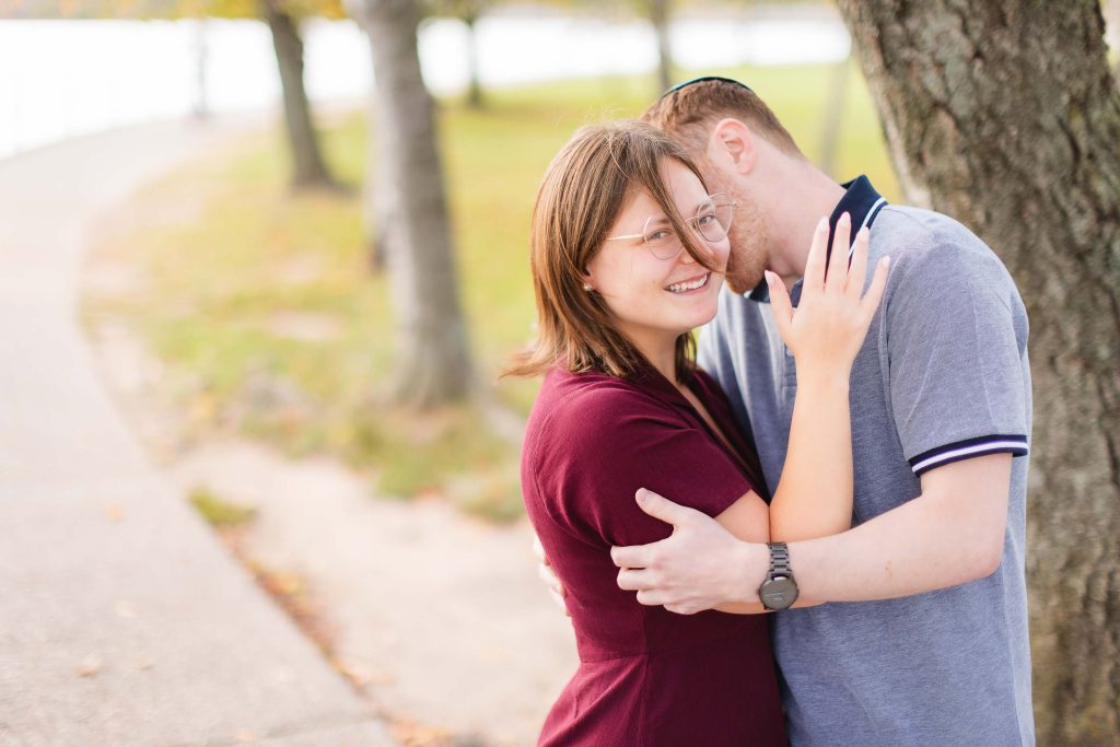 A man and woman are hugging in front of a tree at the Tidal Basin in Washington DC.