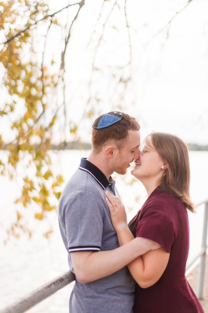 An engaged couple kissing by the water during their engagement session in Washington DC at the Tidal Basin.