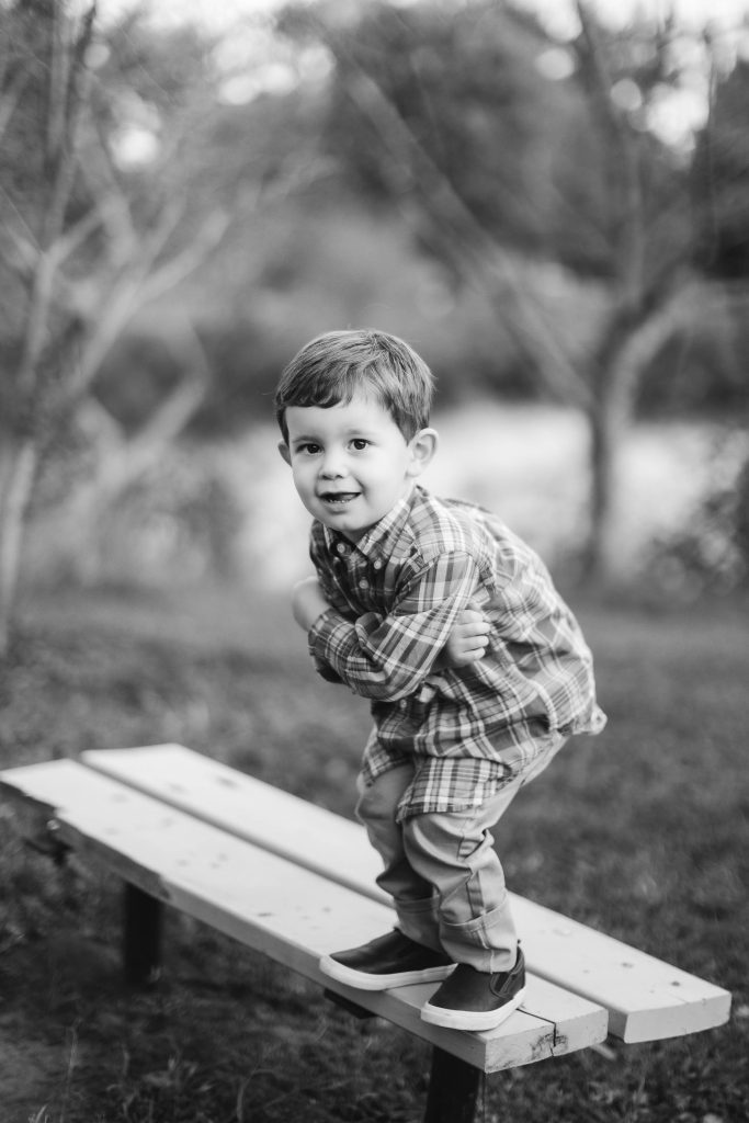 A black and white photo of a little boy standing on a bench in Annapolis, Maryland.