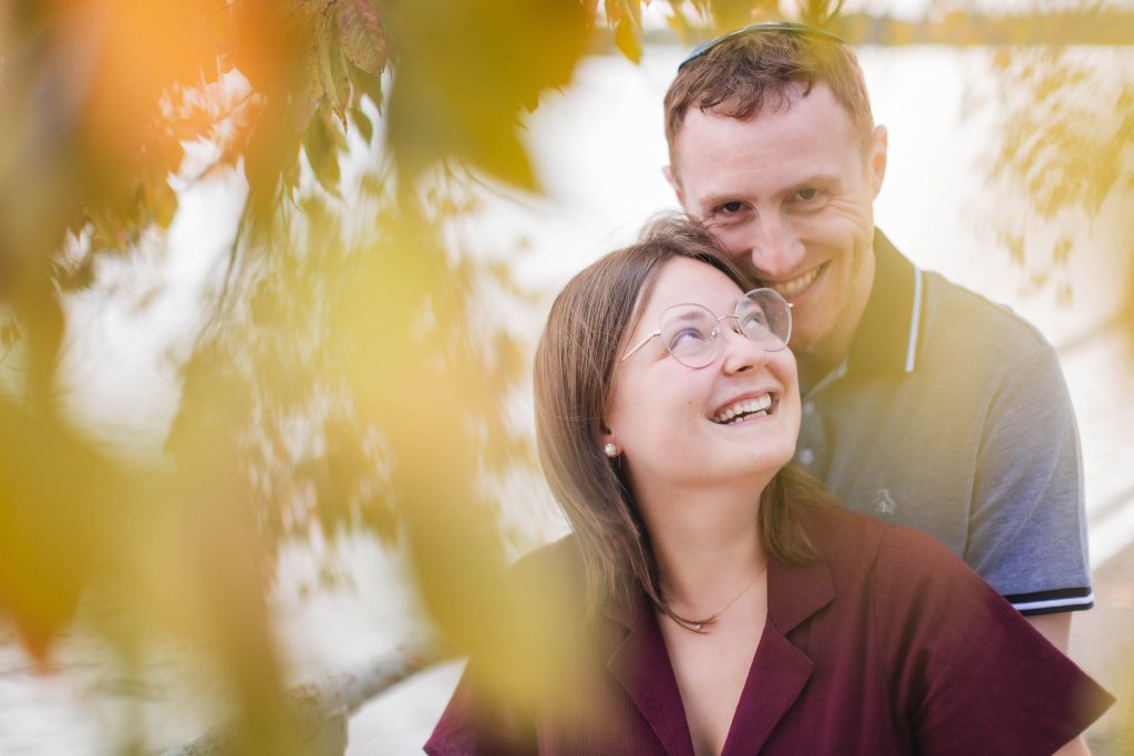 A couple is posing in front of a tree in Washington DC, capturing the surprise wedding proposal.