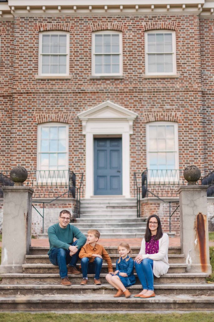 A family from Bowie, Maryland sits on the steps of a brick house, capturing beautiful family portraits.