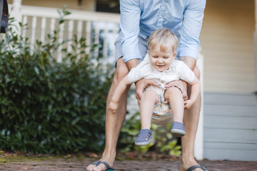 A man is holding a small child at Quiet Waters Park in Annapolis, creating a heartwarming family moment.