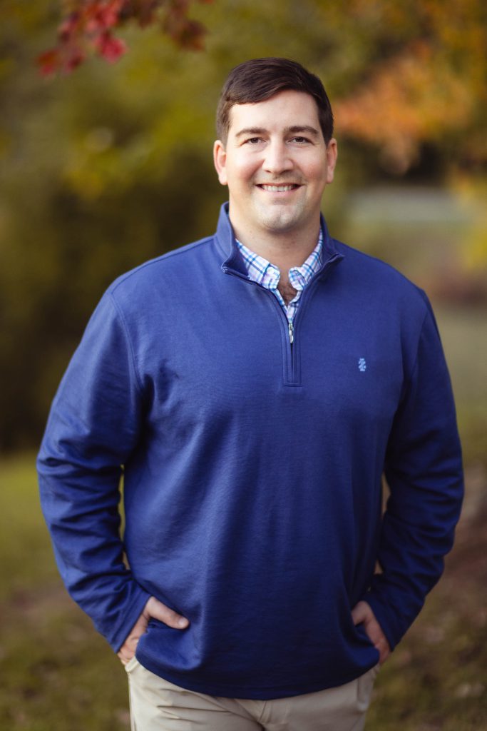 A man wearing a blue sweater and tan pants poses for portraits at Quiet Waters Park.