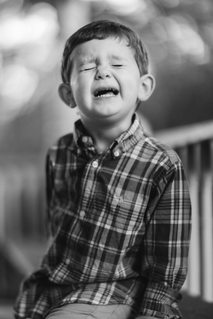A black and white photo of a boy crying, captured during a family portrait session in Annapolis, Maryland.