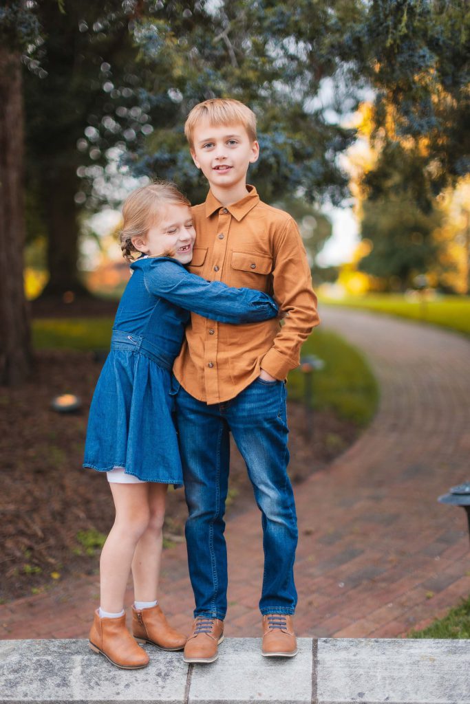 A family hugging in front of a brick walkway in Bowie, Maryland.