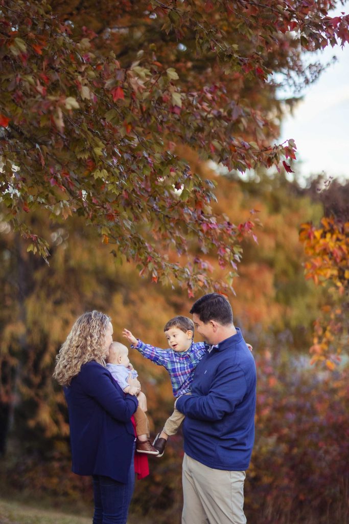 A family from Annapolis, Maryland is standing in front of a tree in the fall for their portraits.