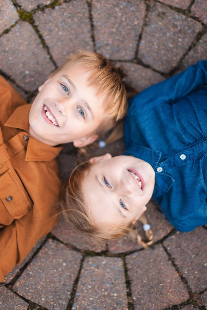 Two children laying on a brick walkway in Bowie Maryland, capturing precious family portraits.