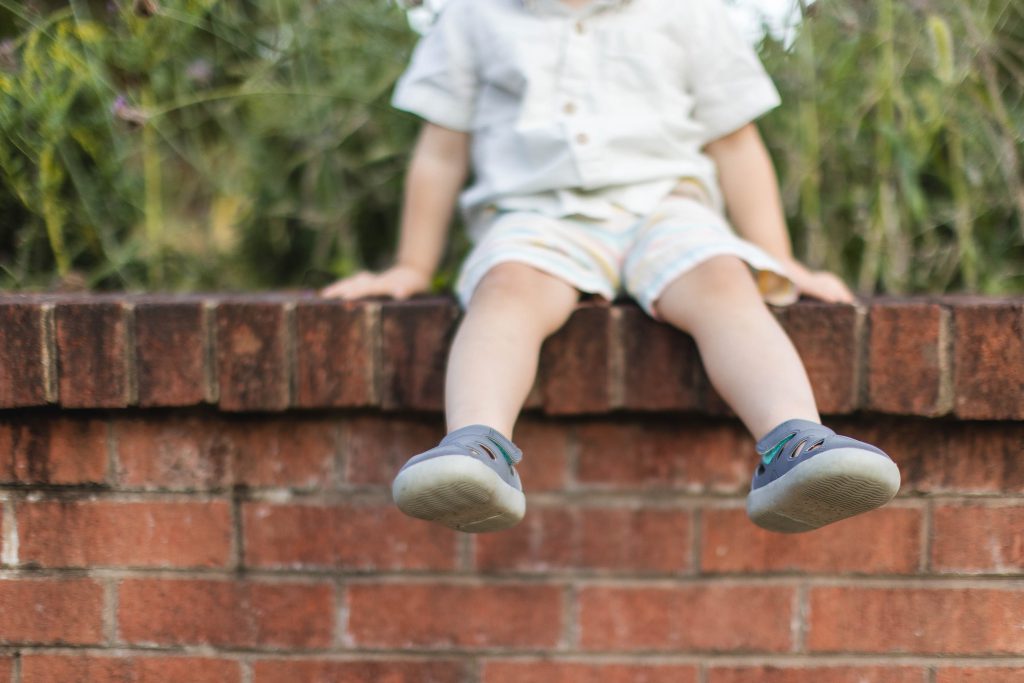 A young boy sitting on a brick wall at Quiet Waters Park.