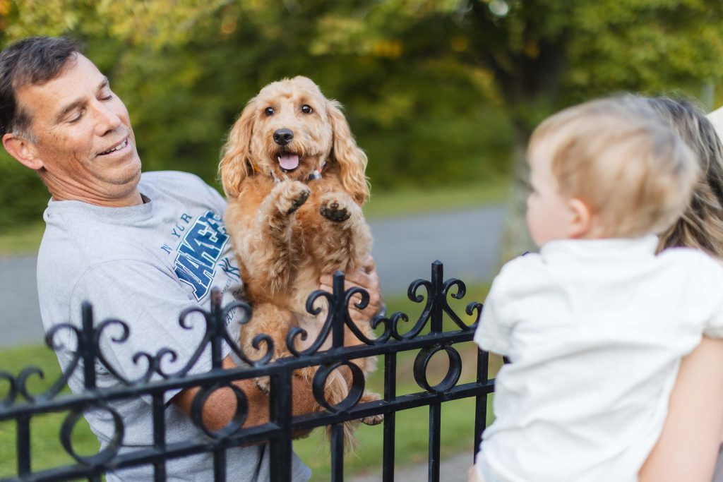 A family holding a dog in front of a fence at Quiet Waters Park in Annapolis.