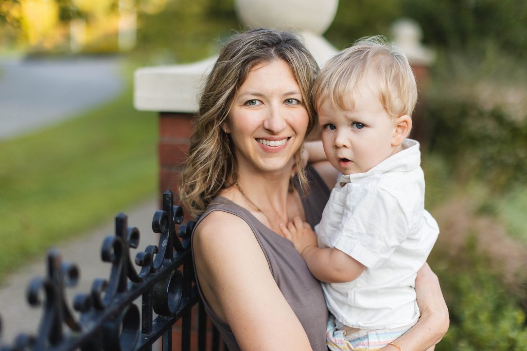 A woman holding her son in front of a fence at Quiet Waters Park for their portrait session.