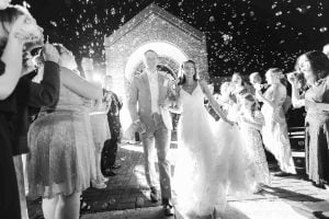 A bride and groom exiting a wedding with confetti thrown at them.