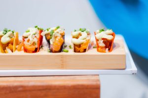 Four mini tacos filled with diced vegetables, sauce, and garnished with chopped chives, arranged on a wooden serving tray—perfect for your Baltimore wedding or a special event at the National Aquarium.
